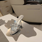 BOW-EMBELLISHED HIGH MULES IN SILVER METALLIC SHEEPSKIN